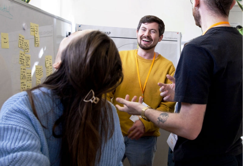 Three people laughing while learning design thinking at one of our courses