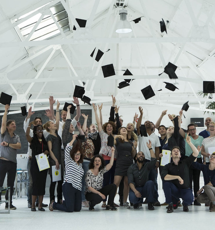 A group of people smiling and throwing their academic hats in the air after graduating one of our courses